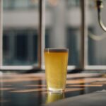 The glass of beer on a wooden table in a cafe.