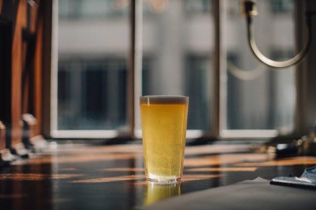 The glass of beer on a wooden table in a cafe.