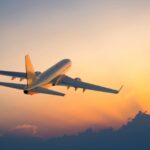 Passenger airplane flying above clouds during sunset