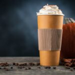 Pumpkin spice latte in a paper cup on dark background