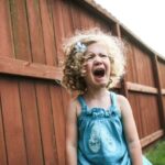 Crying little girl in a garden, wearing blue