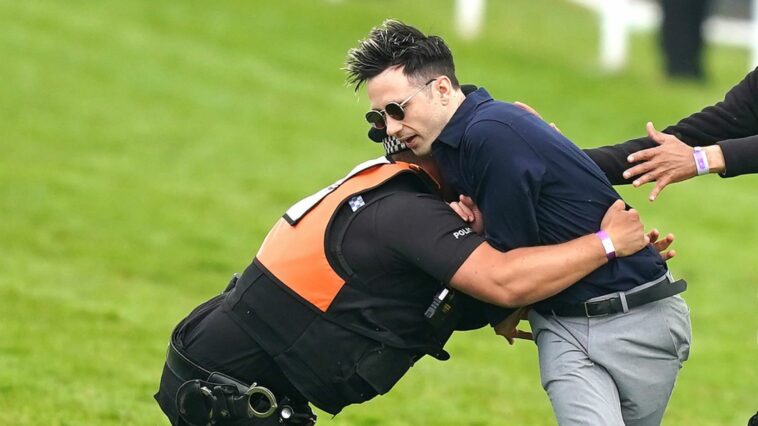 Ben Newman is tackled by police and security on the track at Epsom