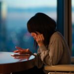 Japanese woman sitting at desk operating smartphone with fingers