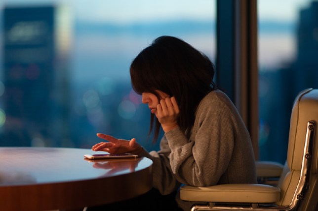 Japanese woman sitting at desk operating smartphone with fingers