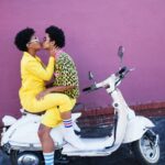 Young couple kissing on the back of a scooter