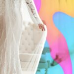 Woman wearing white wedding dress in front of colourful background