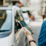 Woman ordering a taxi ride with mobile app on smartphone in the city