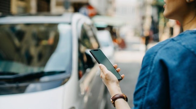 Woman ordering a taxi ride with mobile app on smartphone in the city