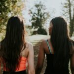 Two young woman walking through a sunny park