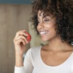 African American woman at home eating an apple