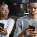 woman looking at partner on his phone