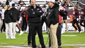 Jimbo Fisher (r.) chatting with Zach Arnett, possibly about how Fisher is going to spend his millions in severance.