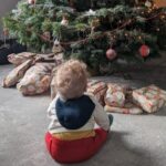 Rose's child sat in front of a Christmas tree