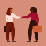 Businesswomen shake hands and look at each other