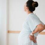 Pregnant Caucasian with back pain in hospital gown