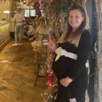 Emma Riley while pregnant, at a restaurant holding birthday balloons.