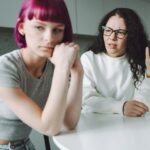 Single working mother and her teenage girl talking sadly in the kitchen