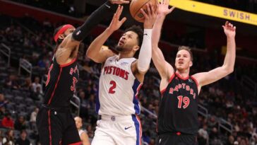 DETROIT, MICHIGAN - DECEMBER 30: Cade Cunningham #2 of the Detroit Pistons drives to the basket between Gary Trent Jr. #33 and Jakob Poeltl #19 of the Toronto Raptors during the first half at Little Caesars Arena on December 30, 2023 in Detroit, Michigan. NOTE TO USER: User expressly acknowledges and agrees that, by downloading and or using this photograph, User is consenting to the terms and conditions of the Getty Images License Agreement. (Photo by Gregory Shamus/Getty Images)