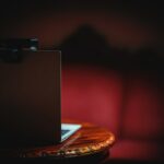 A laptop on a wooden table in a red lit room