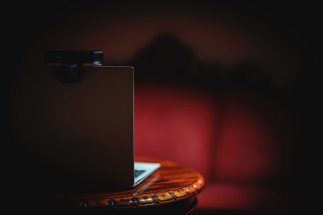 A laptop on a wooden table in a red lit room