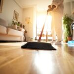 Unrecognizable woman sweeping the parquet floor, window light reflection. Copy space image.