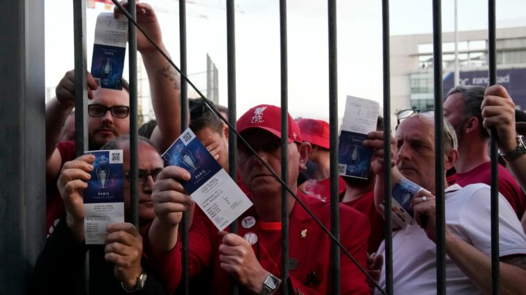 Liverpool fans show tickets and wait in front of the Stade de France prior the Champions League final soccer match between Liverpool and Real Madrid, in Saint Denis near Paris, Saturday, May 28, 2022. Police have deployed tear gas on supporters waiting in long lines to get into the Stade de France for the Champions League final between Liverpool and Real Madrid that was delayed by 37 minutes while security struggled to cope with the vast crowd and fans climbing over fences.