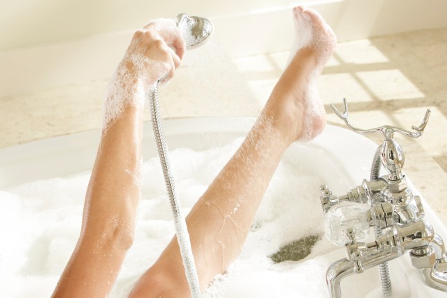 Close-up of a woman's hand taking bath holding a shower head