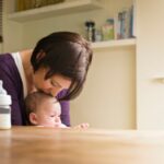 Mother kissing her baby in the kitchen