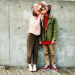 Portrait of couple kissing while hidden behind bouquet of flowers