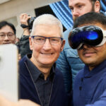 Apple CEO Tim Cook poses for a selfie with a customer wearing a Vision Pro