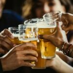 Group of friends toasting beer glasses at table in bar