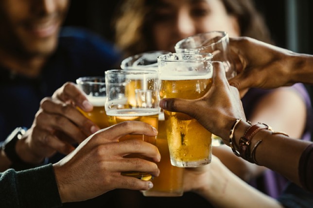 Group of friends toasting beer glasses at table in bar