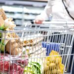 A woman pushing a trolley full of food in supermarket