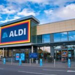 The frontage and brand logo of a branch of German discount retailer Aldi, taken in a local retail park on Wirral, UK on a sunny afternoon