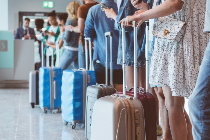 Passengers with luggage waiting in line at airport