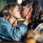 Young lesbian couple kissing each other at restaurant