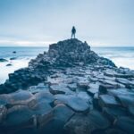 A person standing on the rocks by the sea at the Giant's Causeway, Northern Ireland