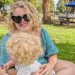 Rose Stokes sitting on the grass outside in a sunny park with her son