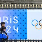 French Gendarmes walk past a banner for the forthcoming Paris 2024 Olympic Games outside The National Assembly - Assemblee nationale in Paris on May 5, 2024.