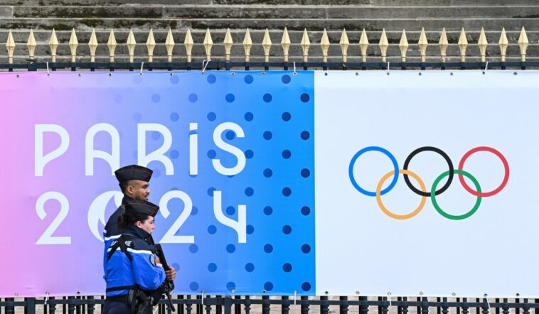 French Gendarmes walk past a banner for the forthcoming Paris 2024 Olympic Games outside The National Assembly - Assemblee nationale in Paris on May 5, 2024.