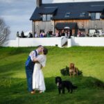 Flic in her wedding day, kissing her husband with her dogs next to them