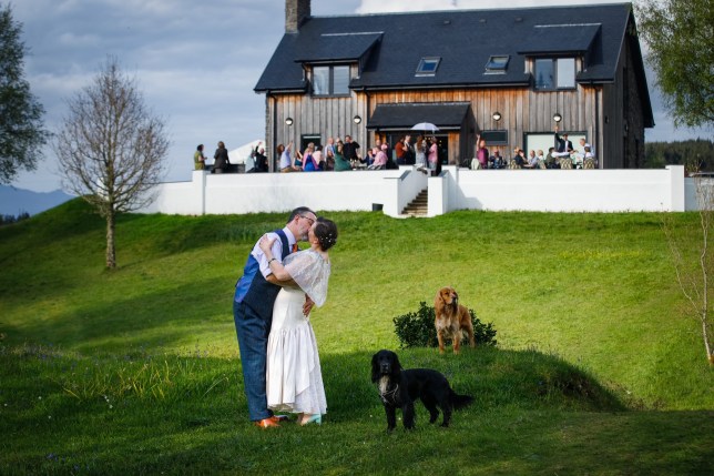 Flic in her wedding day, kissing her husband with her dogs next to them