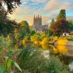 An exterior view of Hereford Cathedral across the River Wye at sunset