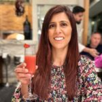 a woman in a restaurant posing with a cocktail.