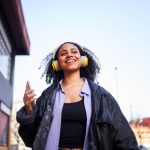 Cheerful young woman listening to music with a mobile in the street