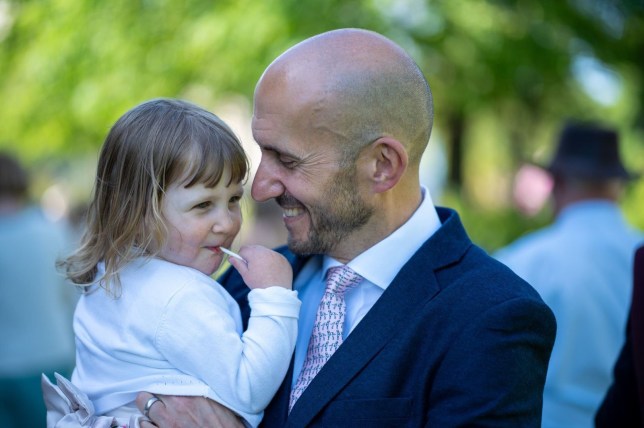 Ryan in a suit, holding his daughter - both are smiling