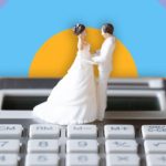 Bride and groom cake toys on top of a calculator