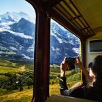 Woman taking photo with smartphone of Jungfrau while riding in train