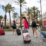 women pull suitcases across a square in Ibiza