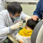 This handout picture courtesy of the Eye & Ent Hospital of Fudan University shows Dr Yilai Shu examining a young patient at the Eye & ENT Hospital of Fudan University in this image taken on April 17, 2024